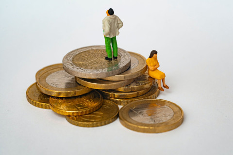 Stack of coins with man looking to the sky and a woman sitting on the coins appearing to be concerned.